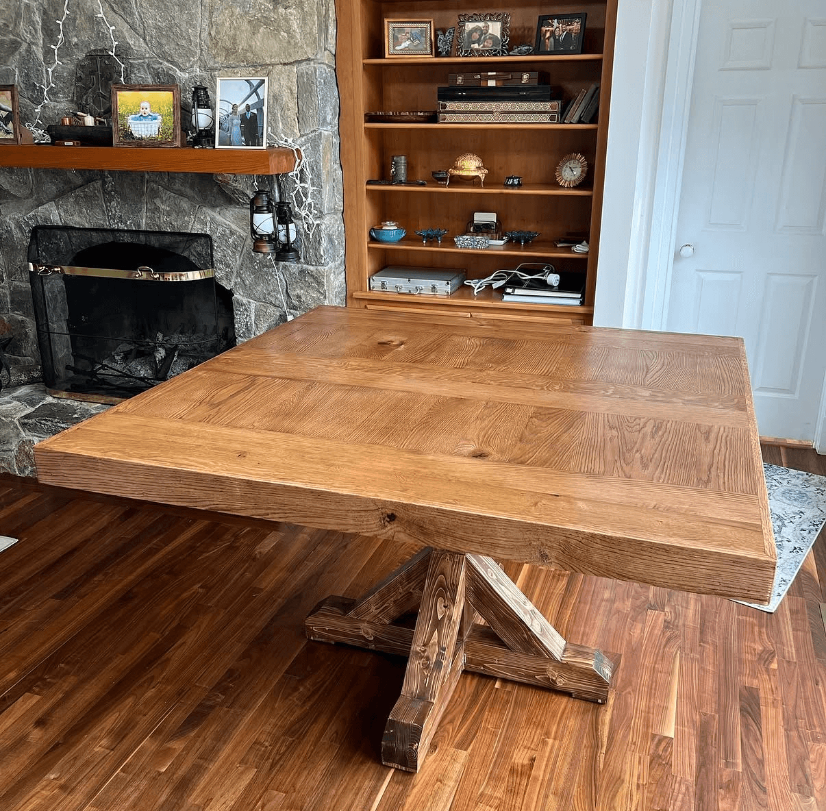 Wooden dining table with a broad rectangular top and a braced pedestal base